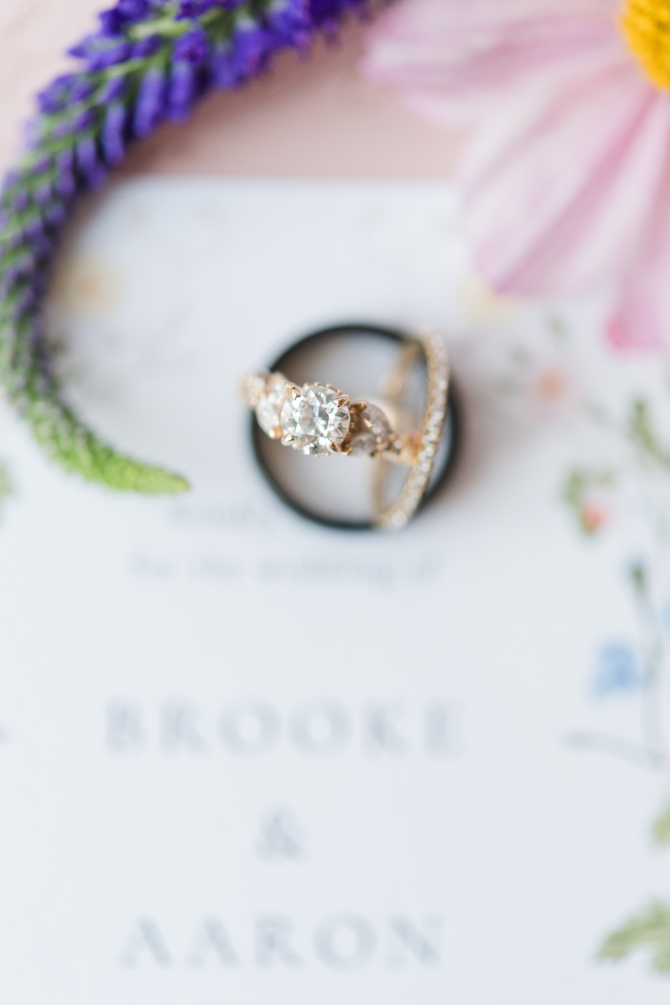 Details of a bride's engagement ring standing with her band and groom's band